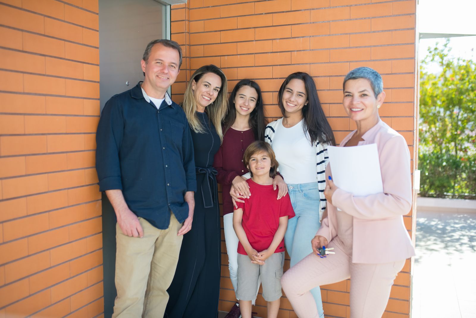 A smiling family with their REALTOR standing outside their new home, celebrating together — this Central Alberta seller's guide is about that outcome