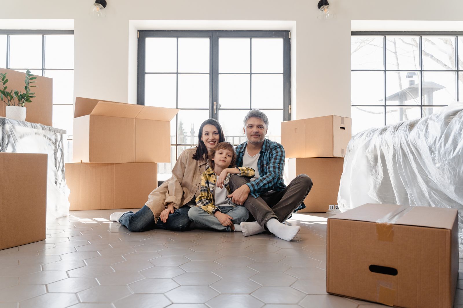 A family relocating to Red Deer, Alberta, sitting together among moving boxes in their new home.