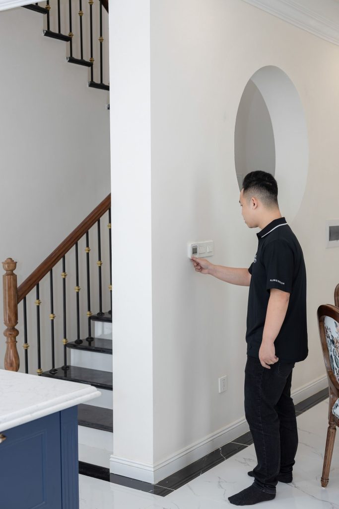 Homeowner adjusting the thermostat to test the furnace before winter in Central Alberta
